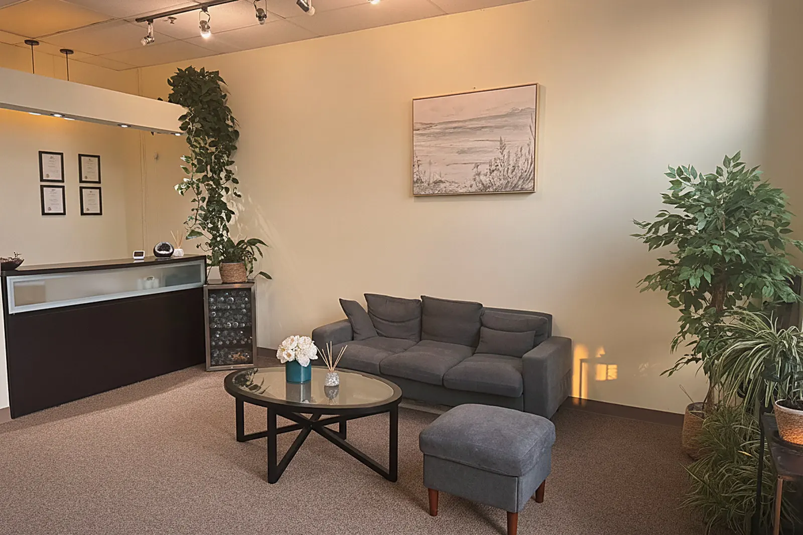 The waiting lounge at Day Massage in Chaska, with a grey sofa, coffee table and warm lighting