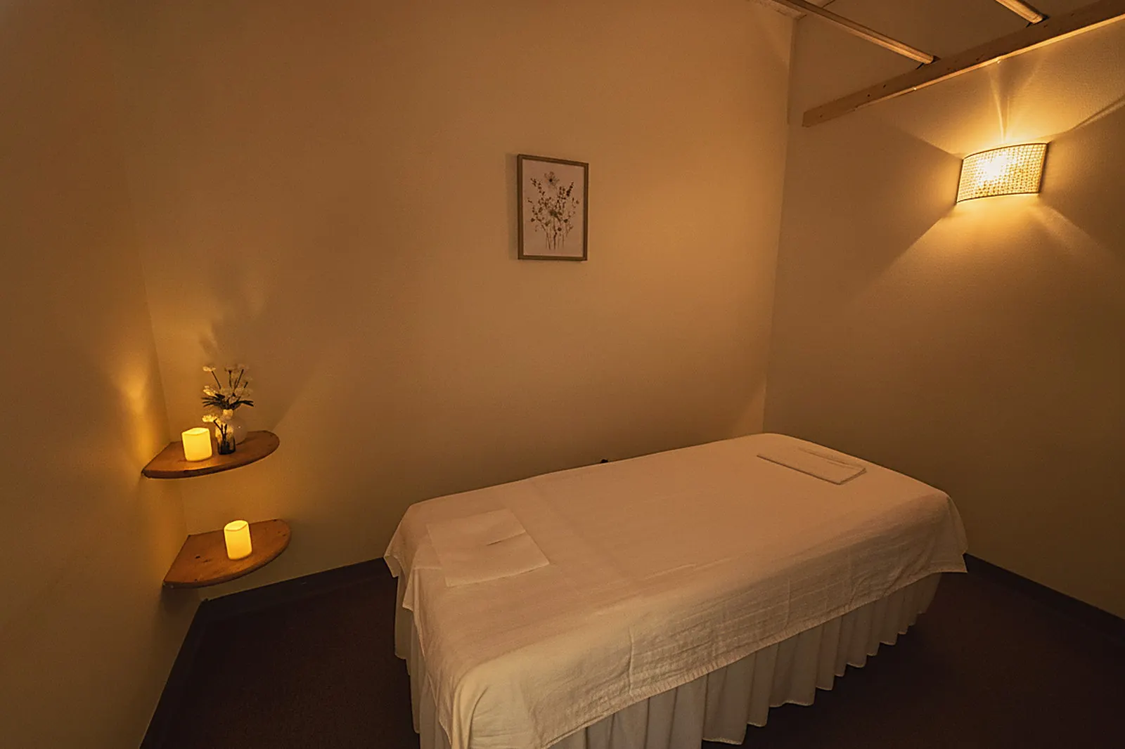 A candlelit treatment room at Day Massage in Chaska with a draped massage table and warm wall sconce